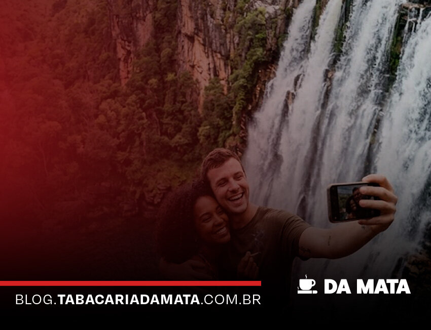 Casal tirando selfie em frente à cachoeira