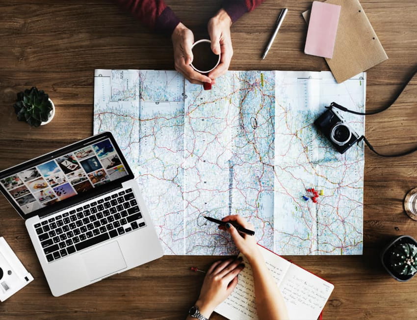 imagem superior de duas pessoas pesquisando mapa e planejando viagem