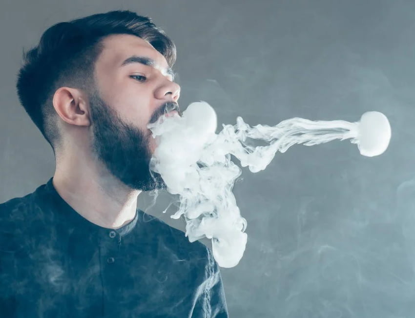homem com barba fazendo bolinha de fumaça