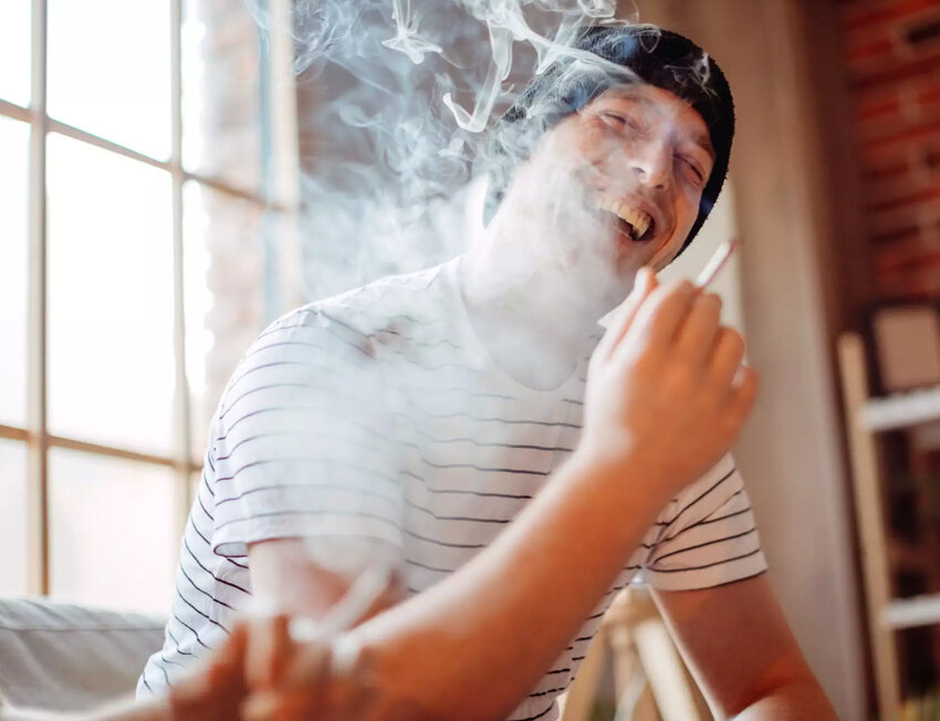 Homem sorridente fumando em ambiente descontraído