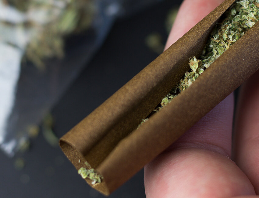 Pessoa enrolando cigarro com tabaco em papel