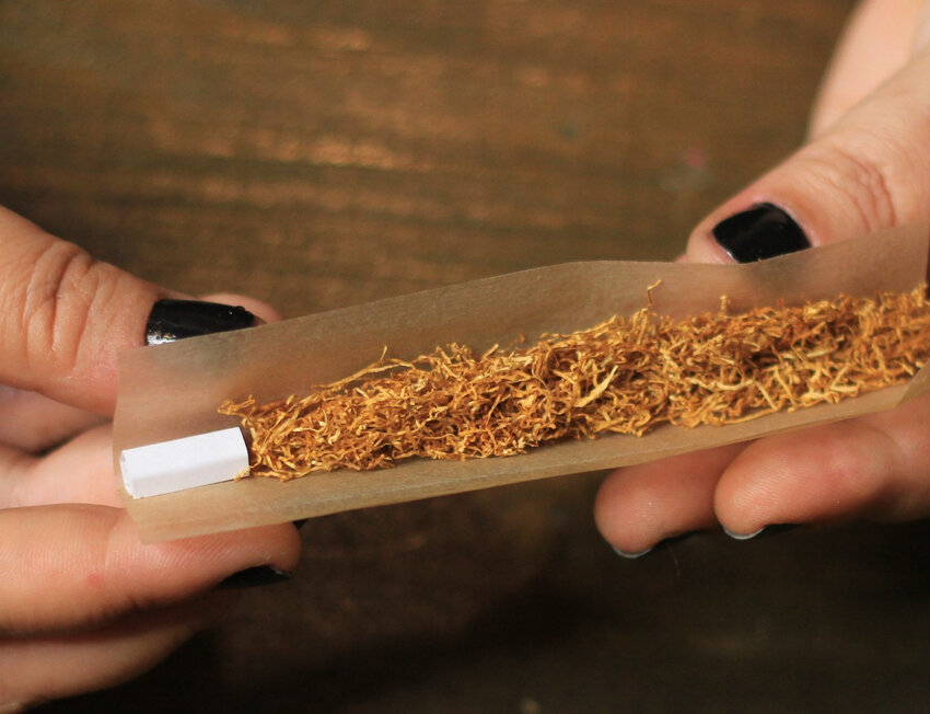 Pessoa enrolando cigarro com tabaco em papel