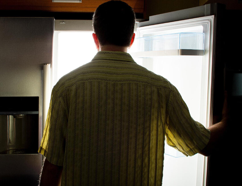 Homem olhando para a geladeira aberta