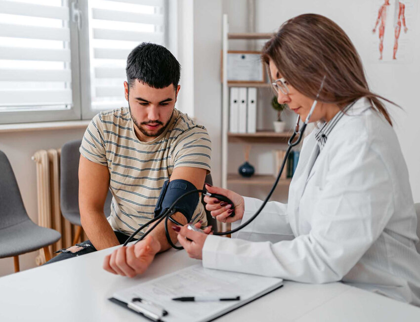 Médica medindo pressão arterial de paciente jovem