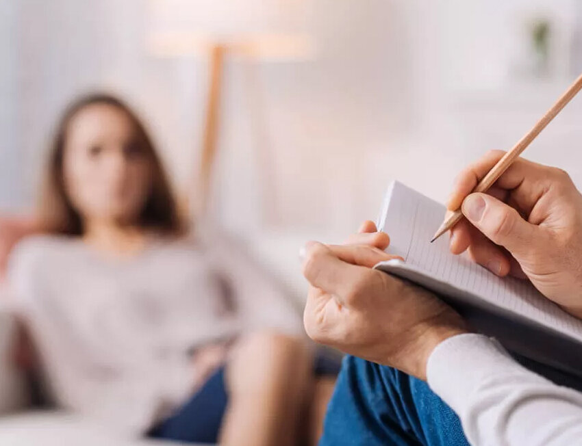Pessoa escrevendo em caderno durante sessão de terapia